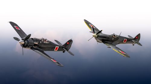 Free Two vintage fighter aircraft soaring through the sky, showcasing historical aviation design. Stock Photo
