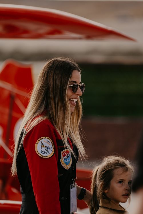 Free Smiling female pilot interacts with a child at an outdoor airshow event. Stock Photo