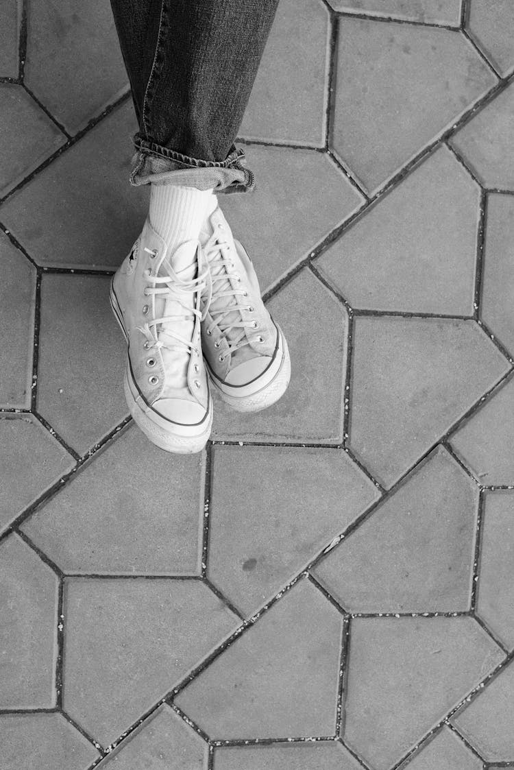 Anonymous Crop Person In Trendy White Sneakers Resting On Concrete Pavement