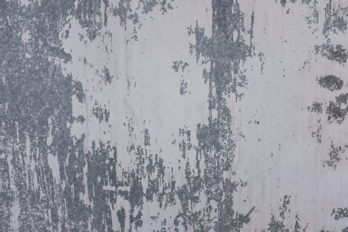 Abstract texture of old shabby metal surface with white paint of modern building on street