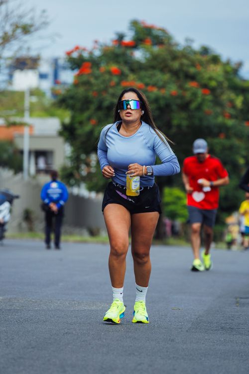 Free Woman running in an outdoor marathon event, wearing colorful sportswear and sunglasses. Stock Photo