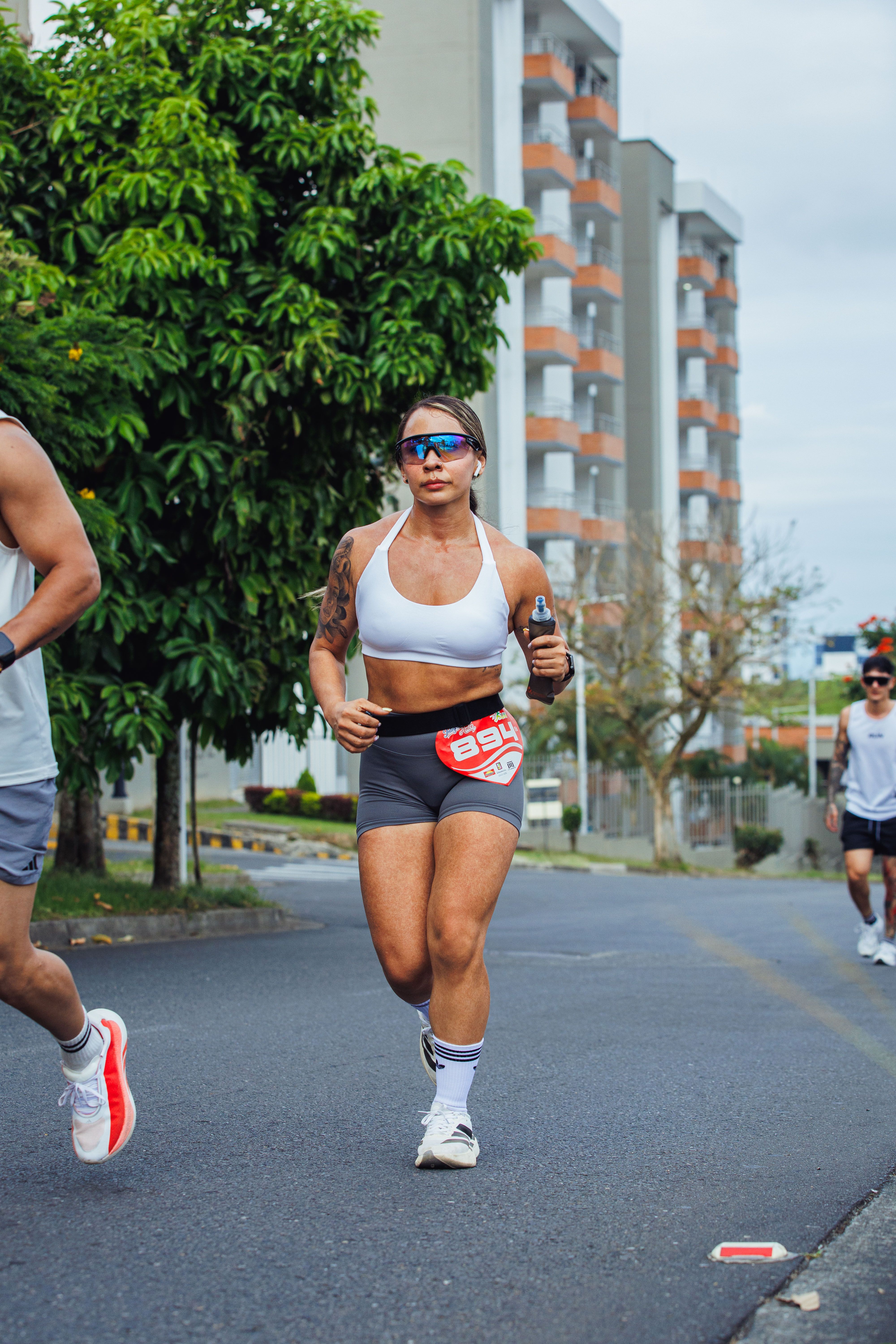 Fit woman jogging in a city marathon with other runners, showcasing determination and athleticism.