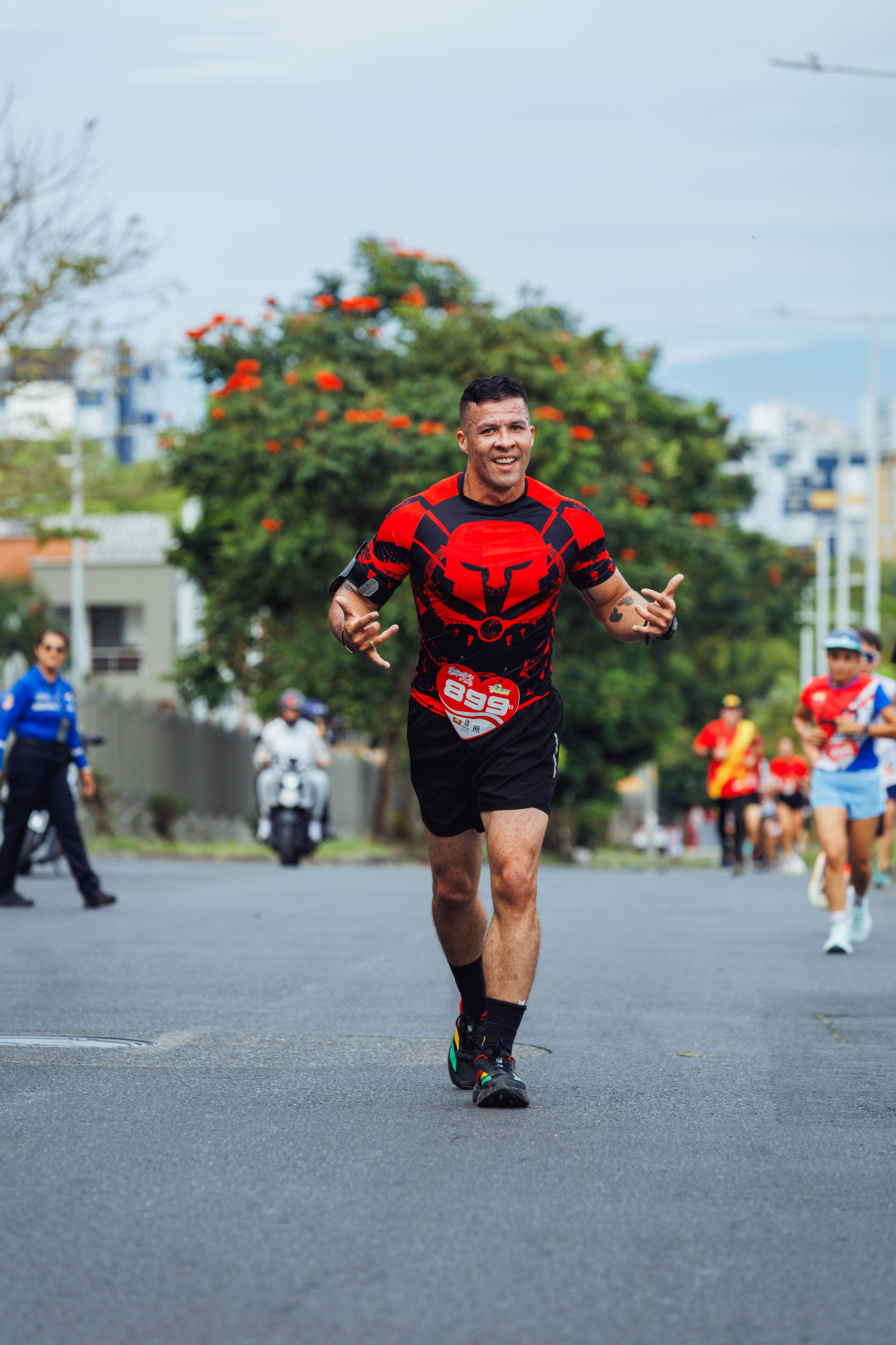 Cheerful male runner approaches marathon finish line with a smile under sunny skies.