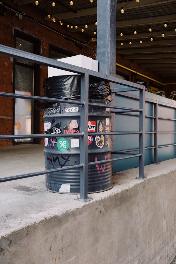 Black Metal Trash Box With Stickers Placed Near Barrier In Modern Building