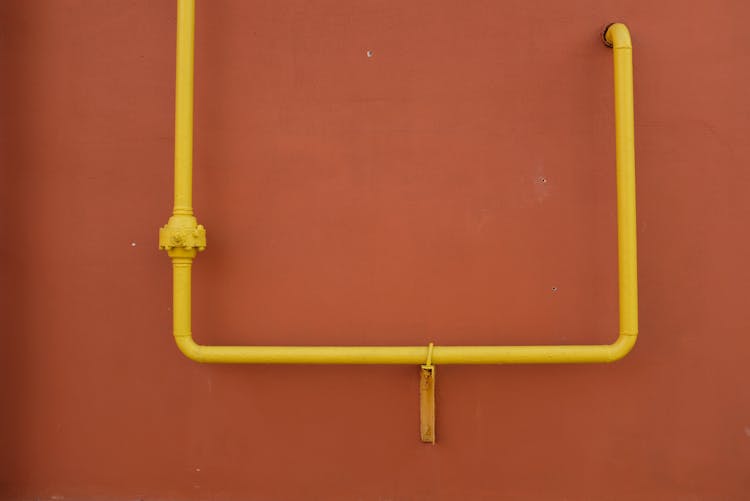 Yellow Metal Pipe On Red Wall