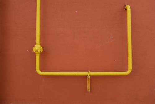 Free Geometric yellow metal pipe on red plaster wall of building on street in city Stock Photo