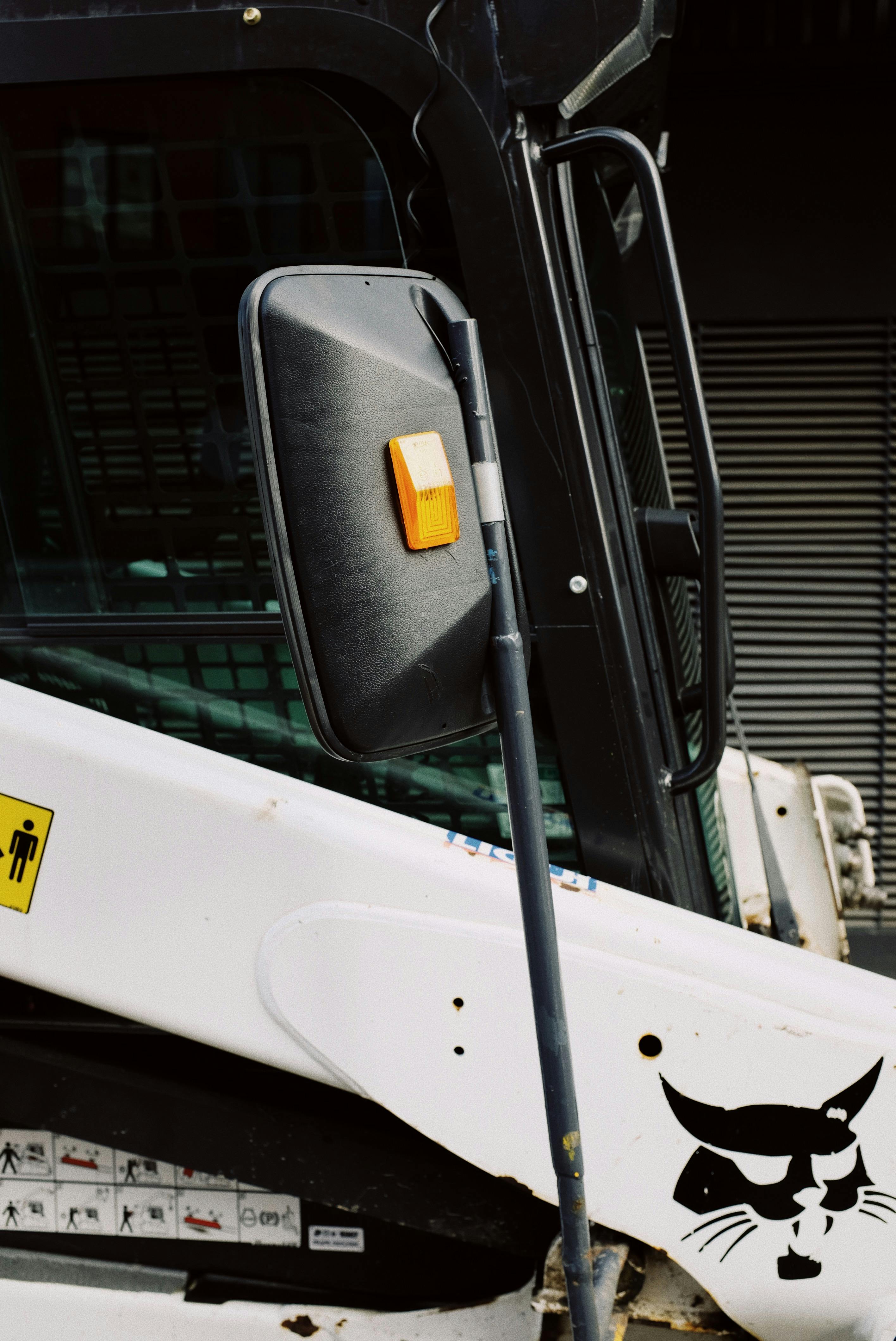 rearview mirror of small truck parked near warehouse