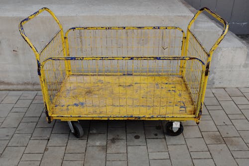 Old metal cart placed near concrete wall of building