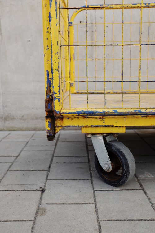 Free Close-up of a rusty yellow utility cart on a paved surface, showcasing texture and color contrasts. Stock Photo