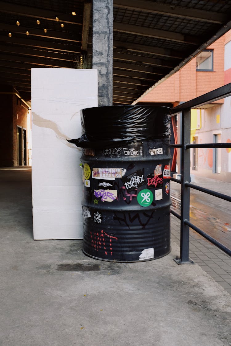 Black Plastic Trash Bin Beside Metal Railing