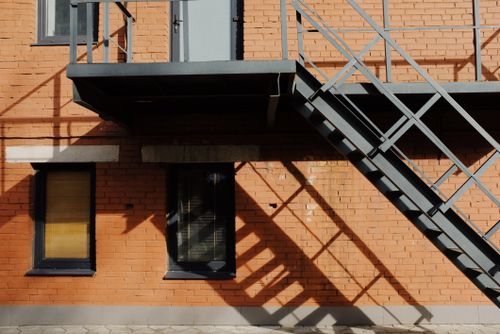 Free A contemporary brick building facade with metal stairs in daylight, casting intricate shadows outdoors. Stock Photo