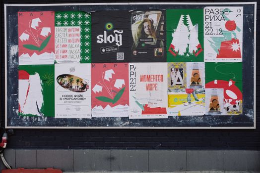 A vibrant urban bulletin board with a variety of colorful posters in Russian.