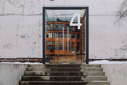 From below of modern building facade with number four on glass entrance door and stairs