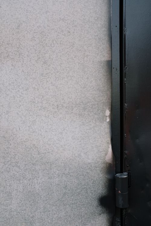 Free Black painted metal entrance door hinge with torn aged and grungy wallpaper surface Stock Photo