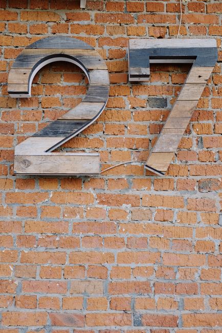 Artistic display of wooden number 27 on a rustic brick wall, perfect for design inspiration.