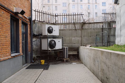 Photo of an urban industrial setting with brick walls and air conditioning units outdoors.