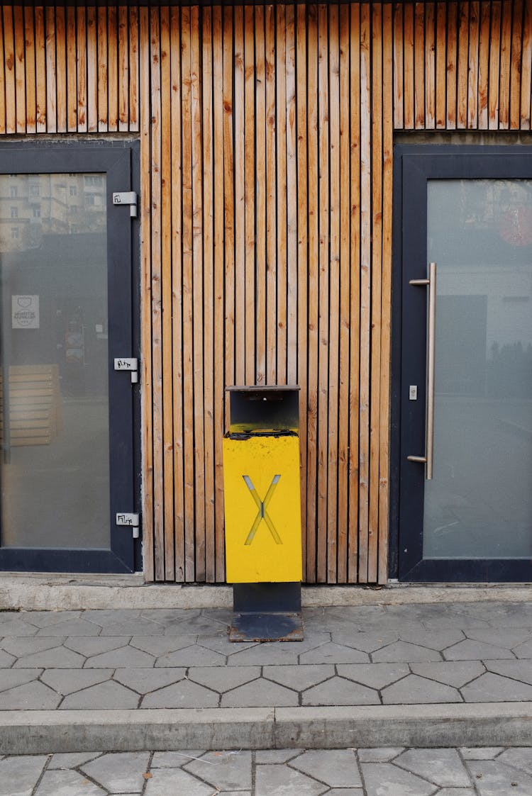 Bin On Street Pavement Near Glass Door