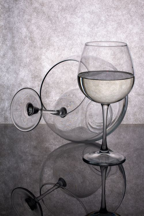 Free Artistic composition of two wine glasses with reflections on a glossy surface. Stock Photo