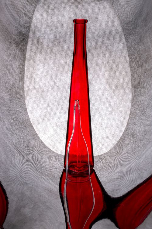 Free Striking red glass bottle on a gray textured background, creating an artistic visual effect. Stock Photo