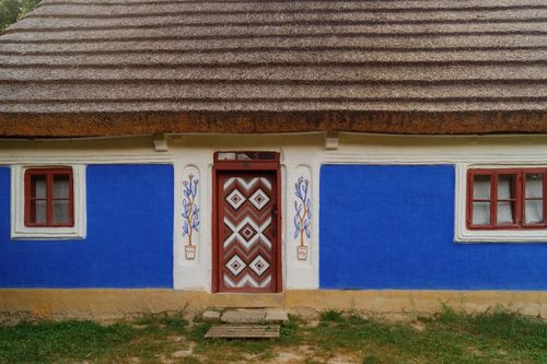 Free Charming traditional Ukrainian mud hut with vibrant blue walls and thatched roof in Kyiv open air museum. Stock Photo