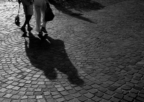 Free Black and white image of two people casting shadows on cobblestones. Stock Photo