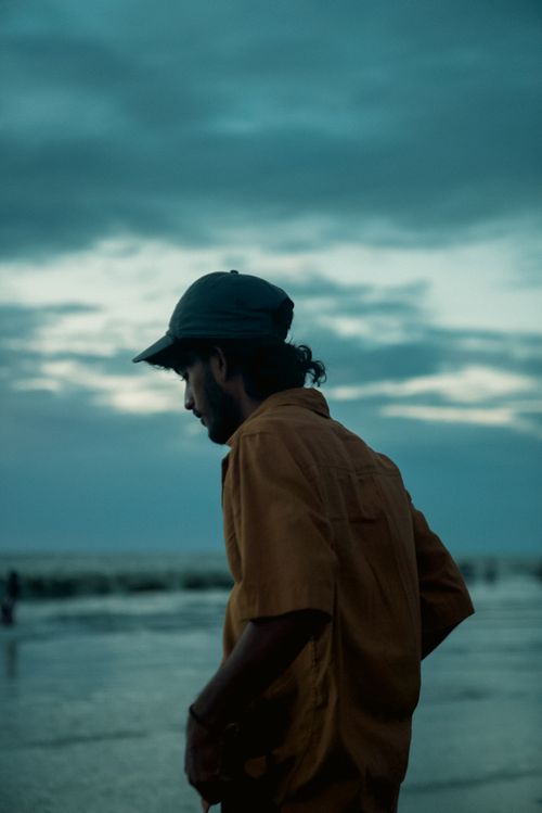 Free A contemplative man in silhouette on a twilight beach in Kochi, India with a serene ocean backdrop. Stock Photo
