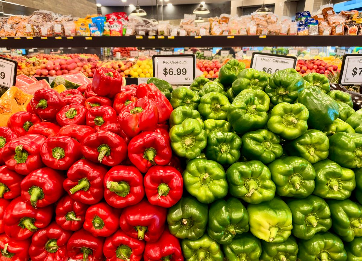 Fresh red and green bell peppers on display in an Australian grocery store.