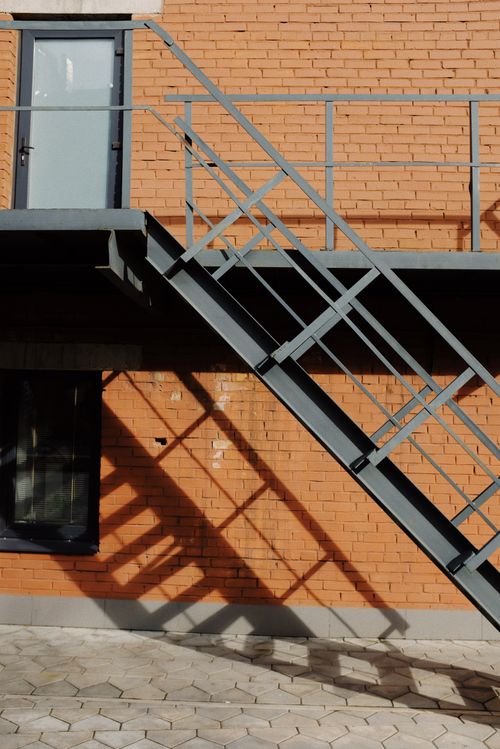 Free Contemporary brick building exterior featuring a steel staircase casting a shadow. Stock Photo