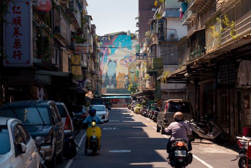 Free A lively street in Taiwan featuring a detailed mural and local activity, capturing urban life. Stock Photo