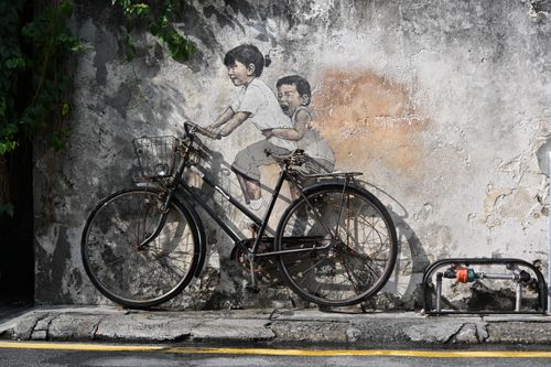 Free Bicycle leaning against wall with street art mural depicting playful children, Penang, Malaysia. Stock Photo
