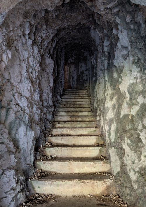 Free Explore the mysterious underground stone tunnel with worn stairs. Stock Photo