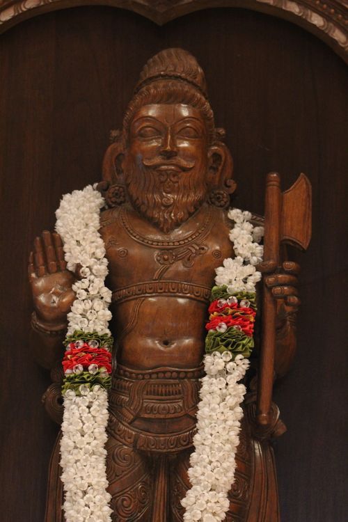 Free Intricate wooden sculpture of a Hindu deity adorned with floral garlands, showcasing cultural artistry. Stock Photo
