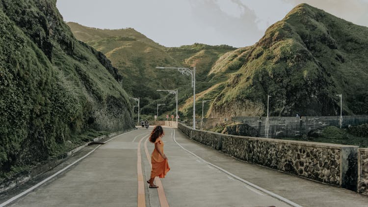 Woman Wearing Orange Dress In The Middle Of The Road