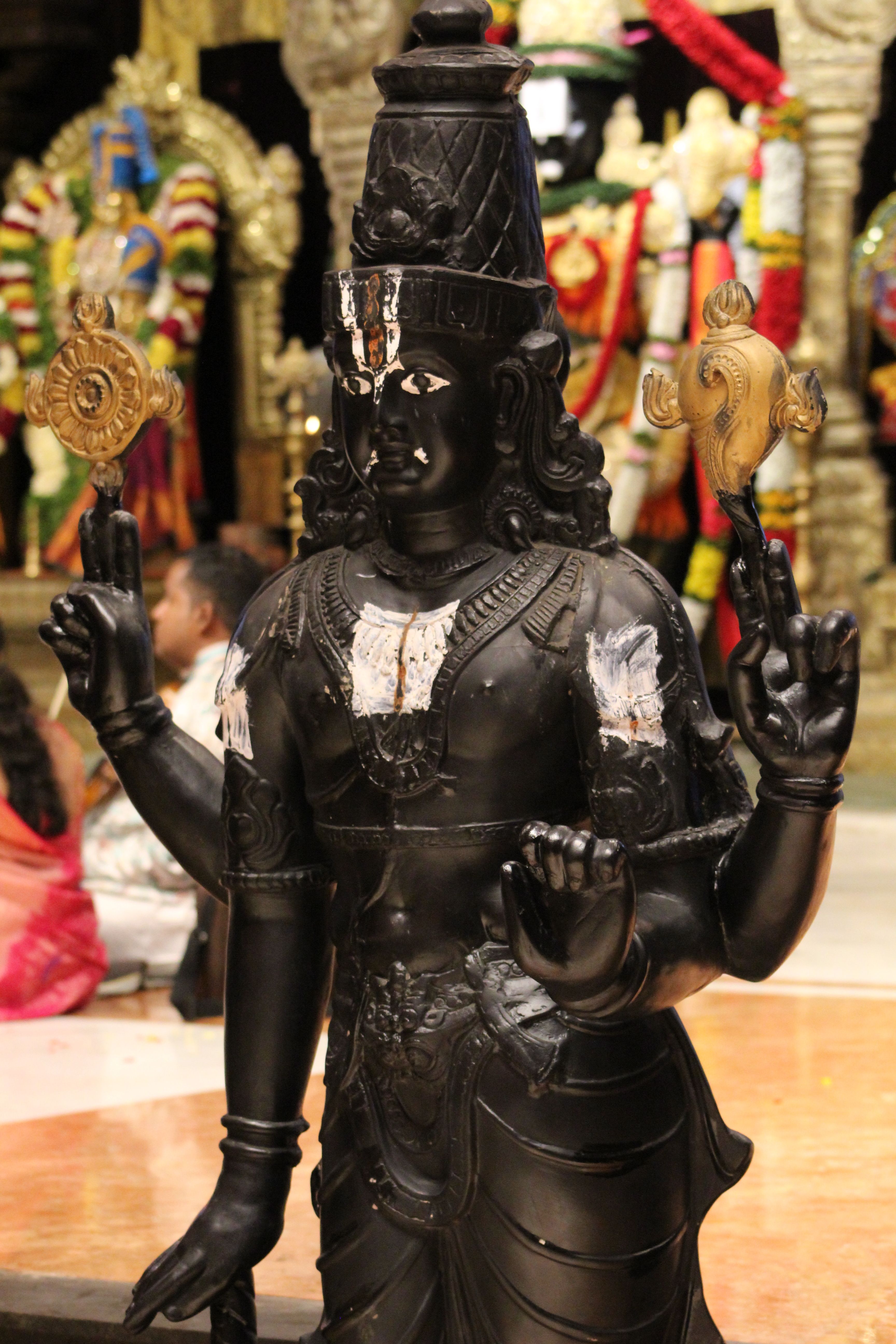 A detailed Vishnu statue inside a vibrant Indian temple.