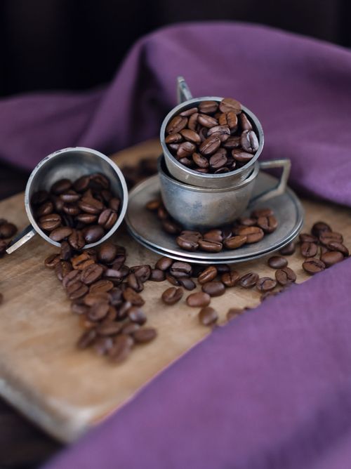 Free Close-up of coffee beans in metal cups on a wooden tray with purple fabric. Stock Photo