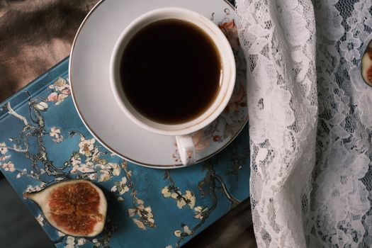 Elegant coffee cup with figs and lace on artistic background for a serene atmosphere.