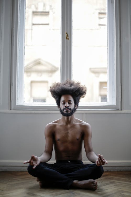 Topless Man Sitting Near Window Doing Yoga