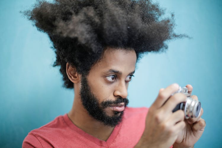 Young Ethnic Man Using Retro Photo Camera On Blue Background