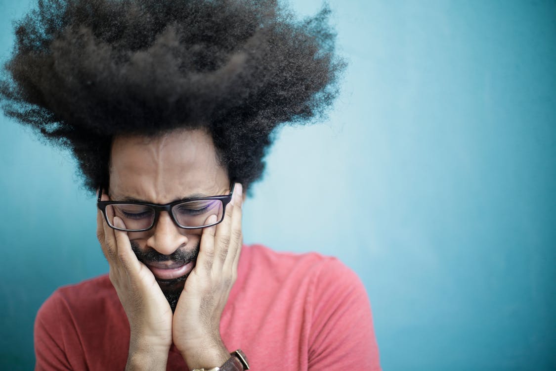 Man in Red Crew Neck Shirt Wearing Black Framed Eyeglasses Crying