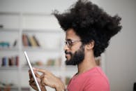 Man in Red Crew Neck Shirt Holding White Tablet Computer