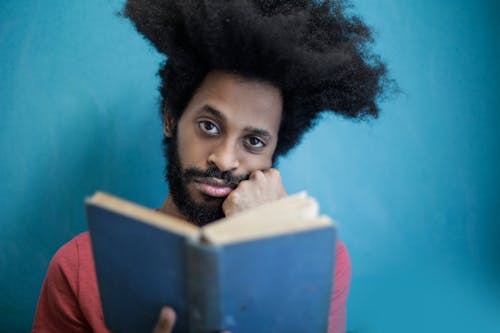 Free Man in Red Shirt Holding Blue Book Stock Photo