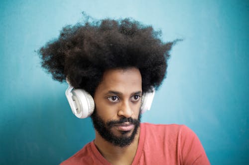 Content ethnic man in casual outfit using white headphones