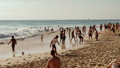 Free Vibrant day at a Bali beach with people enjoying the sun and waves. Stock Photo