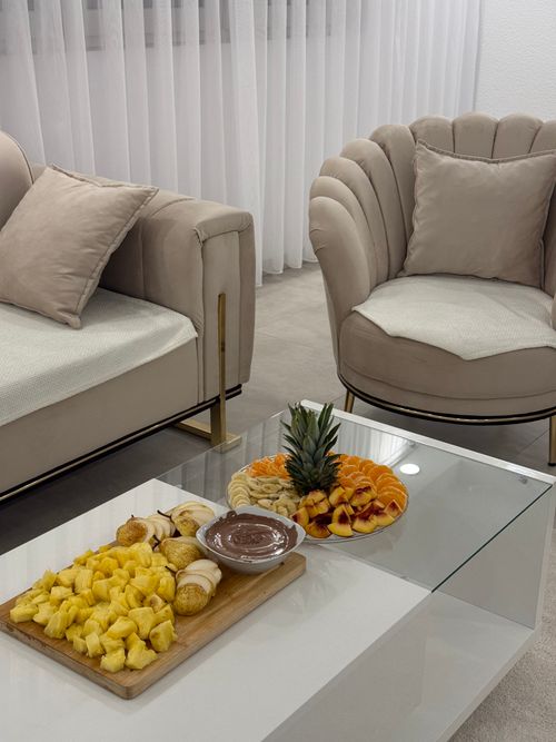 Free Stylish living room with plush armchairs and a fresh fruit platter on a glass coffee table. Stock Photo