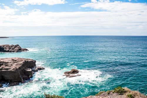 Free Stunning seascape with clear blue waters and rocky coastline under a bright summer sky. Stock Photo
