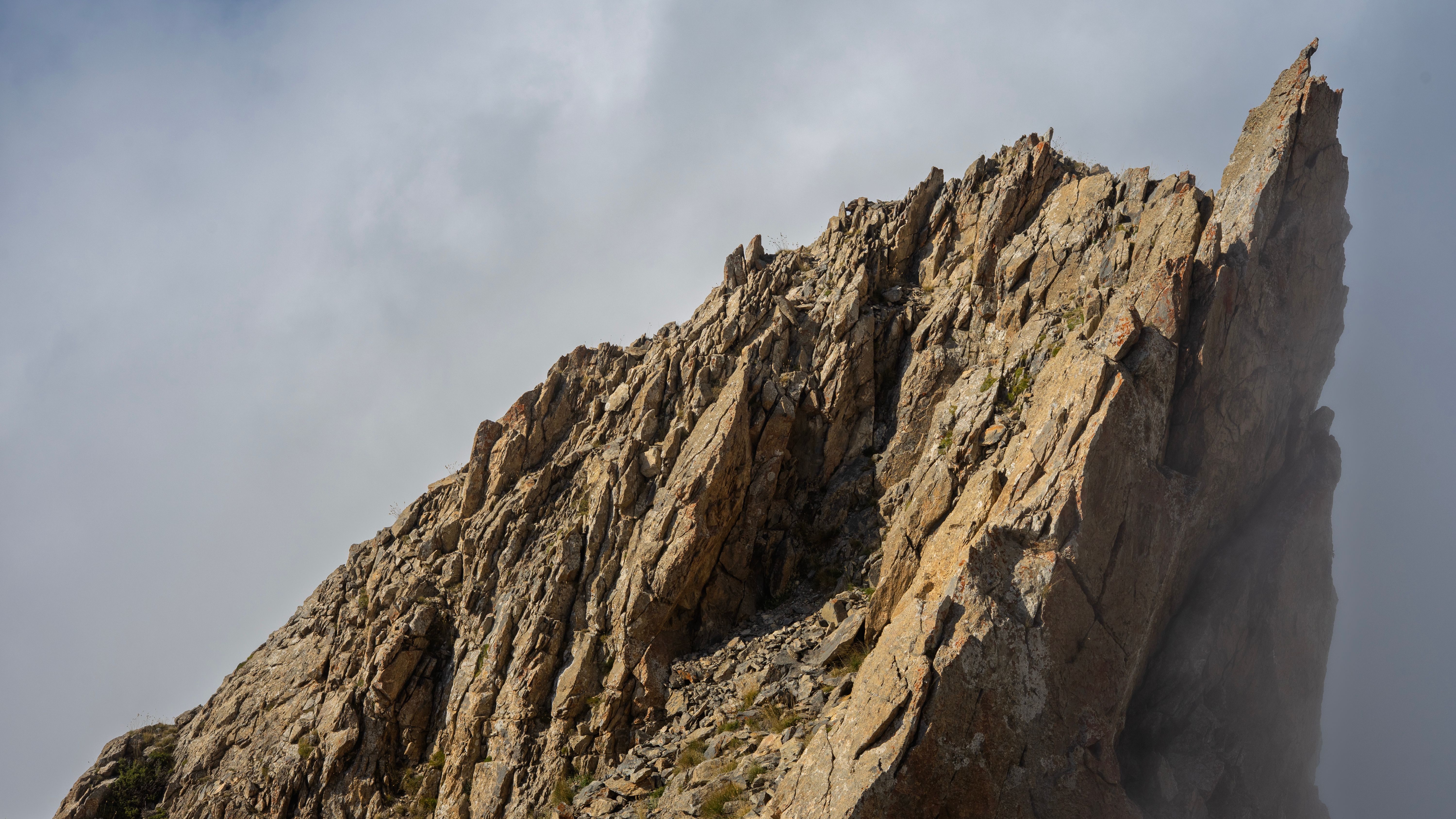 Fotomural Un imponente pico rocoso rodeado de nubes, que muestra las impresionantes formaciones de la naturaleza.