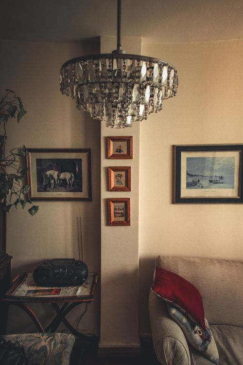 Free Cozy living room featuring a crystal chandelier, art prints, and vintage decor. Stock Photo
