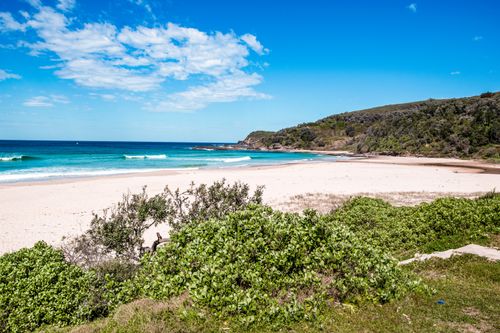 Free A serene coastal scene featuring white sandy beaches, clear turquoise waters, and lush greenery under a bright blue sky. Stock Photo