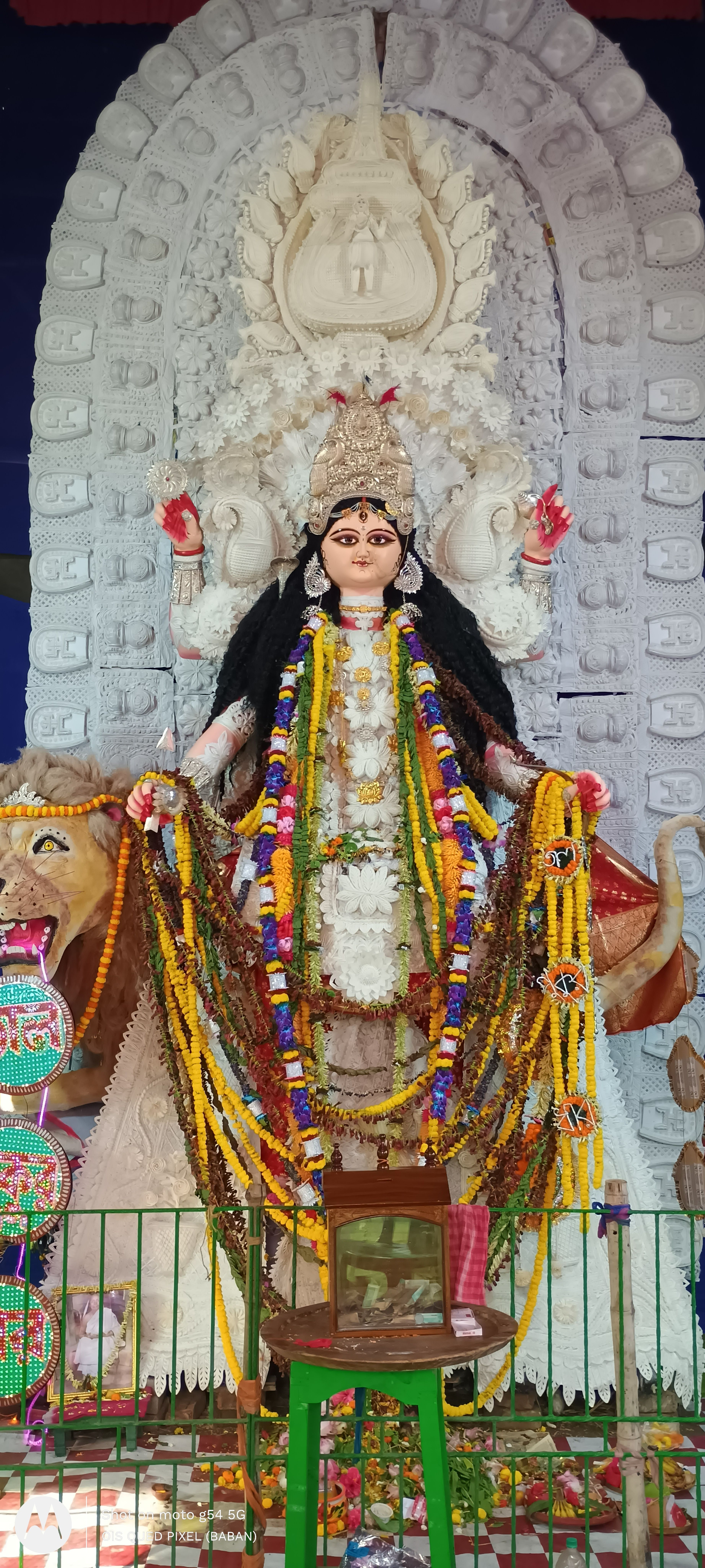 Colorful and intricate idol of an Indian goddess adorned with garlands, set against a decorated backdrop.