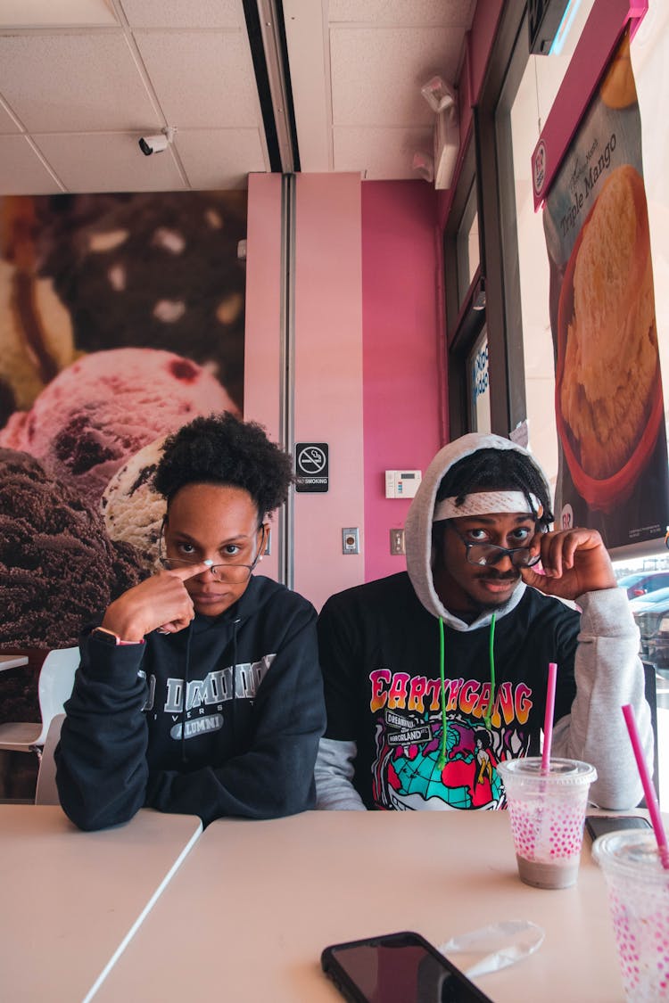 Couple Sitting Holding Their Eyeglasses While In Ice Cream Shop